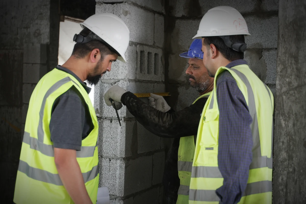 Inspection team in hard hats measuring concrete during a yearly garage observation in Brooklyn