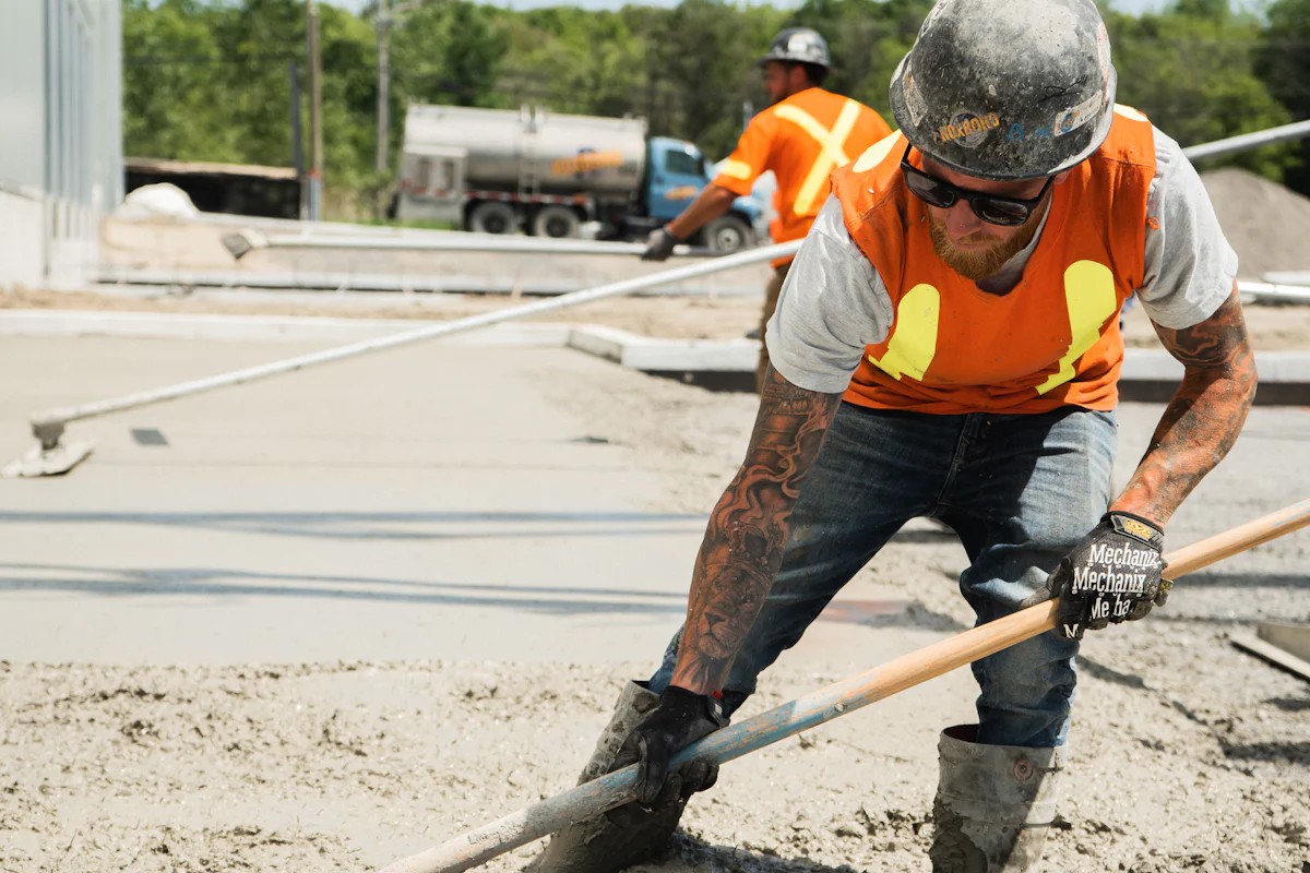 Construction worker in a safety vest placing fresh concrete during a structural repair